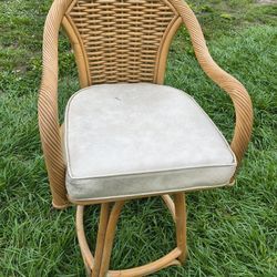 rattan swivel bar stool with a cushioned seat.