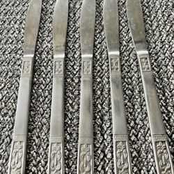 The Customcraft Fleur de Lis 5 Solid Dinner Knives are a set of collectable and retired flatware pieces made of stainless steel. The knives featu