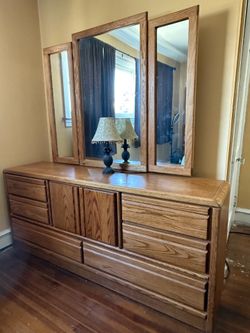 Vintage-style solid oak dresser featuring a matching tri-fold mirror and prominent wood grain