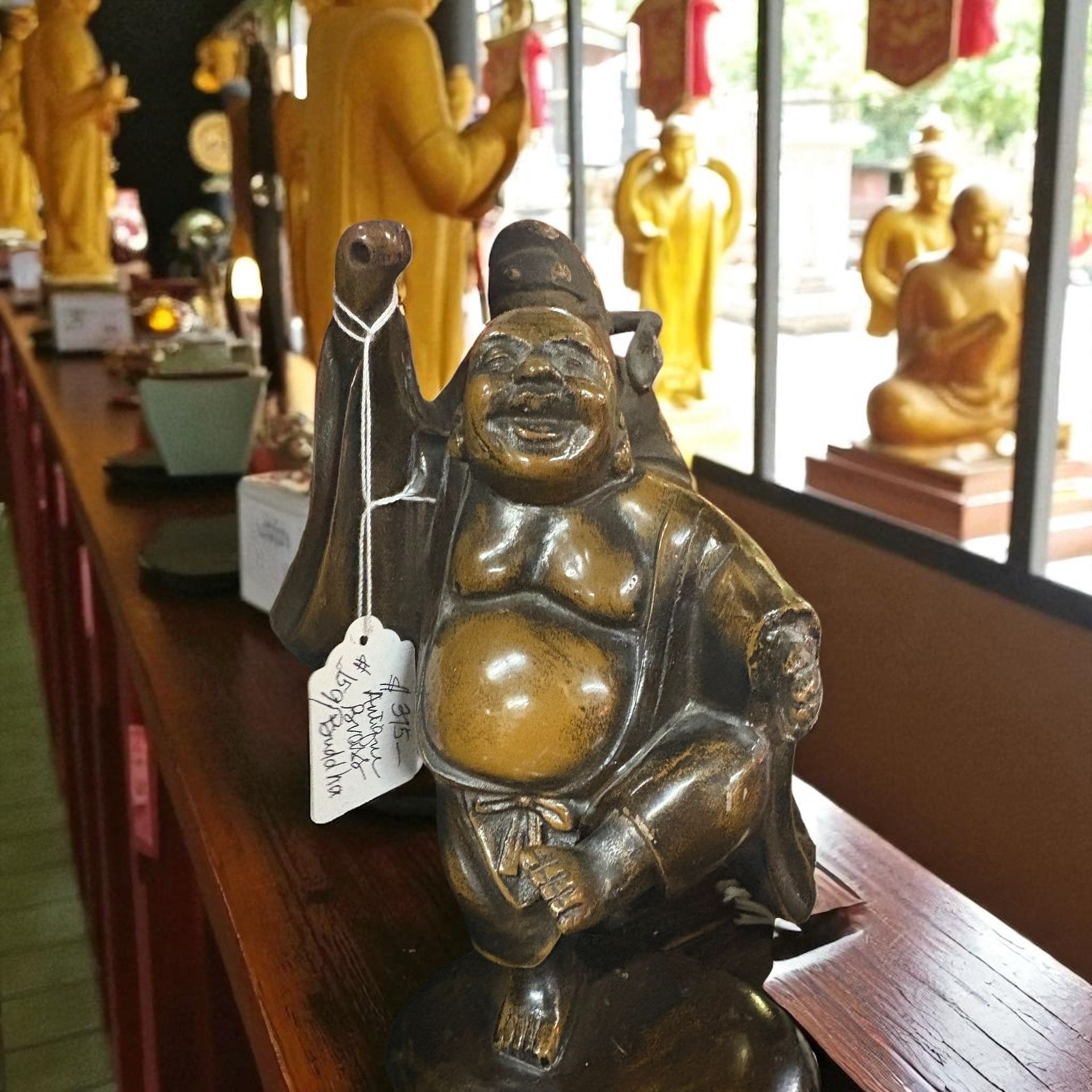 Budai, also known as Hotei or the Happy Buddha, and is identified as an "Antique 159 Buddha" on the attached tag.