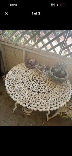 Set Of Victorian-style white cast iron garden table featuring an intricate floral scrollwork pattern