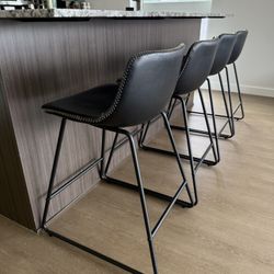 LEMBERI 26” Bar Stools – Set of 4 black faux leather stools with backrests, metal legs, and armless design. Perfect for kitchen islands