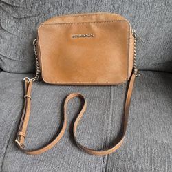 Tan Michael Kors crossbody bag has Saffiano leather exterior with gold-tone hardware. Interior has signature logo lining with several slip pockets. Ba