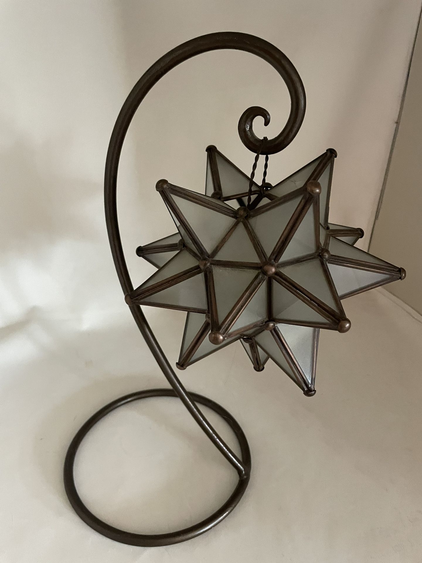 This is a frosted glass and metal Moravian star hanging tea light lantern candle holder with a stand