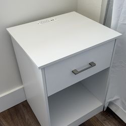 Two white bedside tables with receptacles