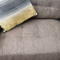 5 Seater Couch Brown Colored With 3 Pillows And With 1 Brown Coffee Table.