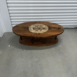 Coffee table with seashells in the middle. Used in good condition with some cosmetic blemishes. The table has a hard plastic coating that covers the e