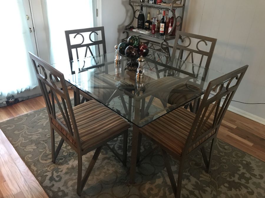 Glass table with four chairs and bakers wine rack.