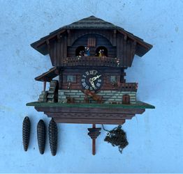 Traditional Black Forest chalet-style cuckoo clock featuring hand-carved wooden architectural details, floral balcony accents, and dancing figurine al