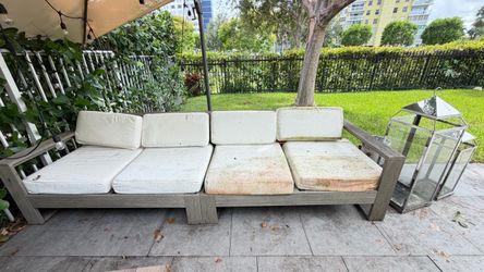 West elm weathered gray wooden outdoor sectional sofa with noticeably stained worn white cushions