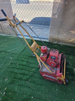 McLane 7-blade reel mower, often recognized by its yellow handle and red housing