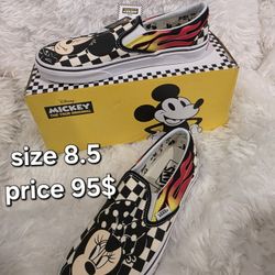 

This is a Vans x Disney Classic Slip-On sneaker featuring Mickey and Minnie Mouse with a checkered flame pattern. 