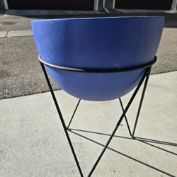 Blue planter with large black metal stand. 