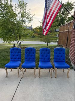 Blue fabric dining room chair features a classic Chesterfield-inspired tufted back and elegant.