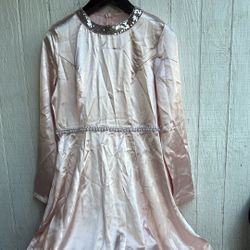 es un vestido largo de color rosa claro con detalles brillantes en el cuello y perlas en la cintura. Debido a que no hay información específica sobre 