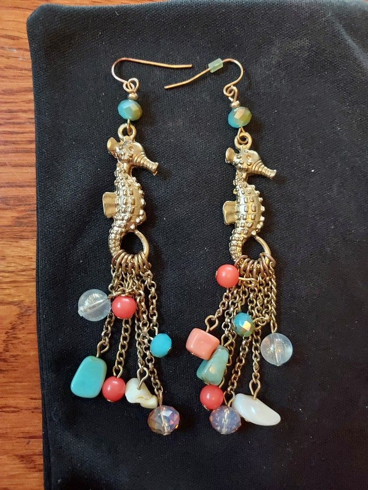 Pair of handmade artisan dangle earrings featuring seahorse charms, chains, and various beads including coral, shell, and glass.
