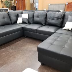 Black faux leather sectional with a matching storage ottoman