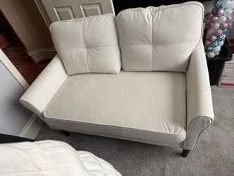Off white small loveseat with button-tufted back cushions and dark wooden legs