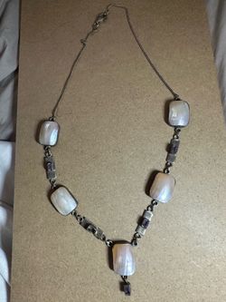 This sterling silver necklace features rectangular white pearls and small purple gemstone accents.