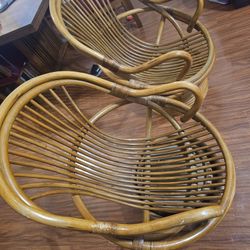 These are vintage, bohemian-style rattan and bamboo swivel lounge chairs featuring a wrap-around design and a circular base.