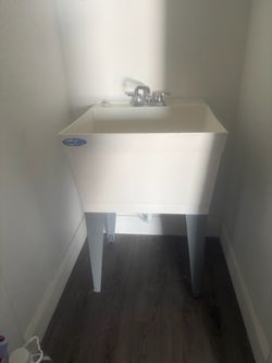 Mustee freestanding utility/laundry sink with steel legs and faucet.