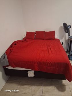 Queen size bed with sheets and comforter and 4 red pillows