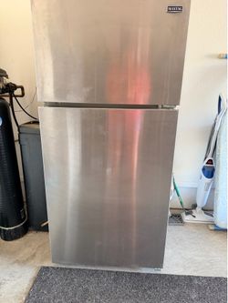 Maytag refrigerator features a sleek stainless steel finish and a classic top-mount freezer design.