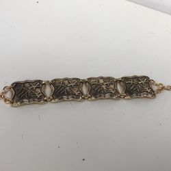 vintage gold-tone link panel bracelet, potentially from the 1950s, featuring Chinese-inspired designs on the decorative panels. 