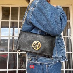 Tory Burch black leather shoulder/crossbody bag featuring a gold-tone chain strap and the signature round logo hardware on the front. Pebbled leather 