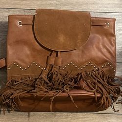 This is a brown faux leather backpack with fringe and stud details, similar to styles from American Eagle Outfitters and Classic Rock Couture