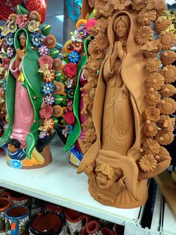 This is a hand-sculpted Terracotta Virgin of Guadalupe clay sculpture made in Metepec, Mexico, traditionally featuring an intricate arch of handmade c