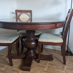 Vintage round dining table with four upholstered wooden chairs