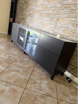 black IKEA BESTA storage unit with glass doors and drawers.