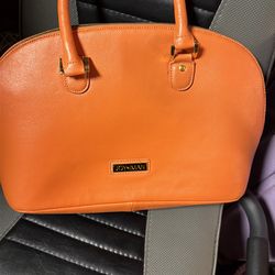 The orange handbag in the image is from the Joy & Iman brand.