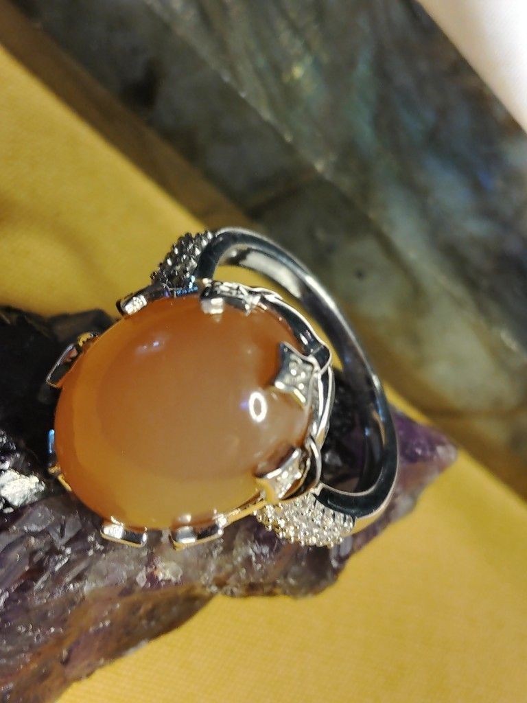 PEACH MOONSTONE, A LARGE CABOCHON LAYERED ON CLUSTERS OF ZIRCON. STERLING- SETTING. SIZE 6