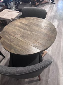 Round Weathered Gray Wood Leaf Table and Upholstered Grey Chairs