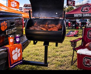 Detachable Tailgate grill with sliding cooking rack and rotating trailer hitch mount.