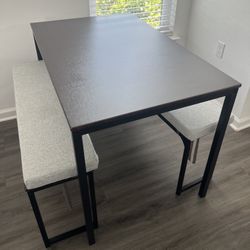 Brown table with black metal framing, with two benches + two cushions