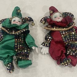 Pair of vintage jester dolls with porcelain faces and hands, adorned in sequined costumes.
