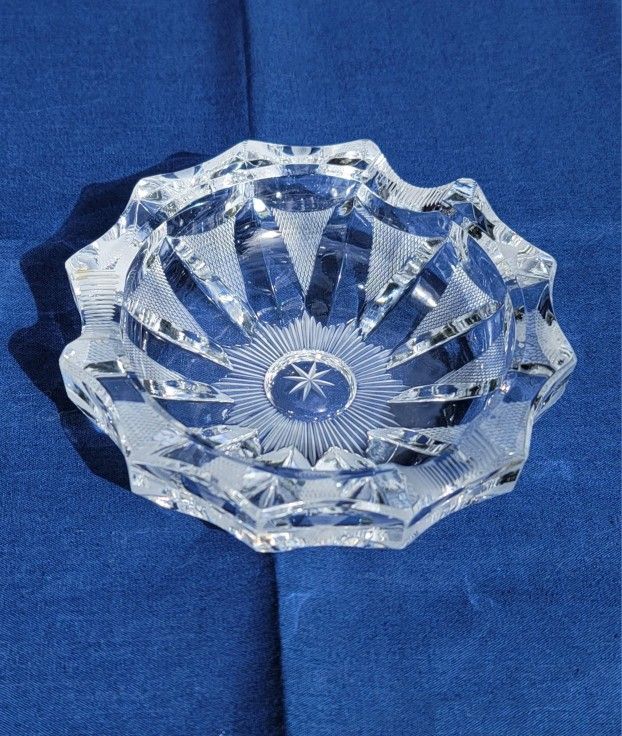 Vintage cut glass crystal ashtray with a starburst pattern. 
It is a heavy, 5" round piece with a faceted design. 