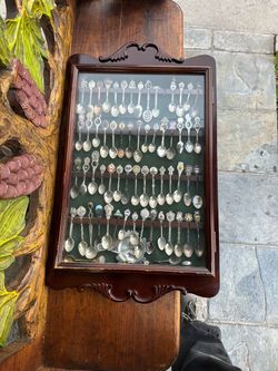 Vintage collection of over 50 souvenir spoons from various global locations and landmarks. The set is housed in a dark wood wall-hanging display case 