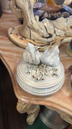 Vintage porcelain trinket box featuring two sculpted swans and delicate gold-accented floral details on the lid