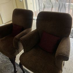 Two Brown Arm Chairs With Red Sparkly Pillows