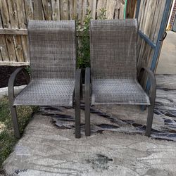 Durable outdoor chairs with breathable mesh sling fabric and sturdy metal frames. These chairs have a dark brown finish on the metal and a textured gr