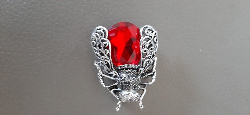 Brooch with a red gem and intricate silver detailing.