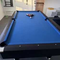 Modern full-size pool table in excellent condition, perfect for a game room or basement. Features a sleek black frame with bright blue felt, sturdy co