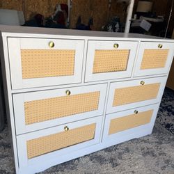 This is a white FOTOSOK 7-Drawer Rattan Dresser with gold-colored handles.
