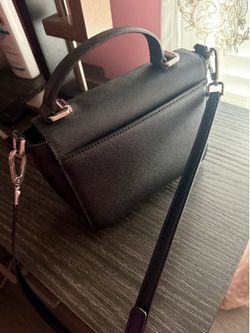 Stylish black crossbody bag with adjustable strap and front zipper pocket.