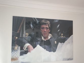 The image is a picture of a framed print featuring actor Al Pacino as the character Tony Montana from the 1983 film Scarface. 