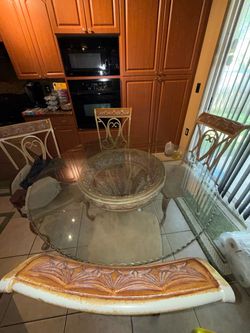 5-piece dining room set featuring a spacious glass-top dining table with an elegant decorative base and 4 matching chairs.